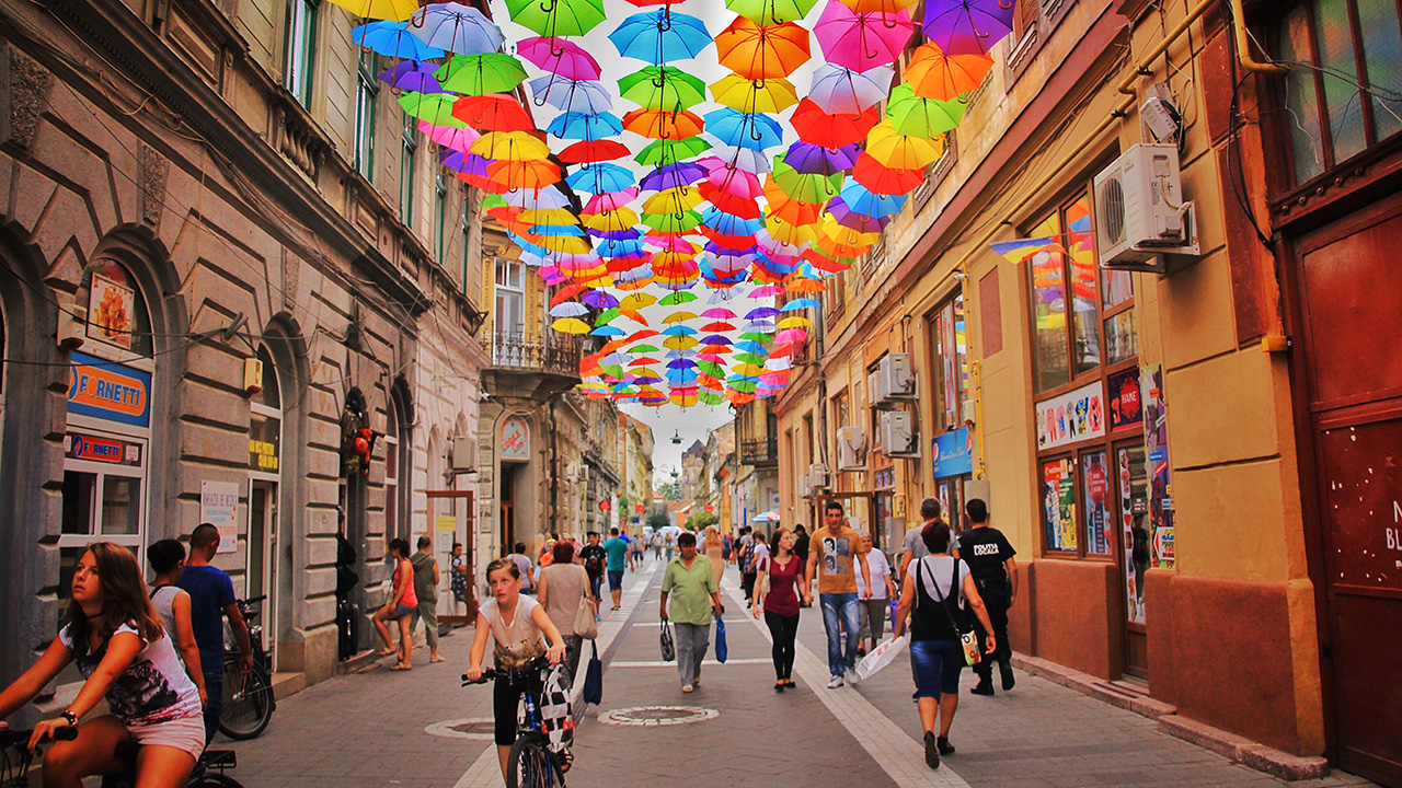 Image of people walking under a ceiling of colorful umbrellas