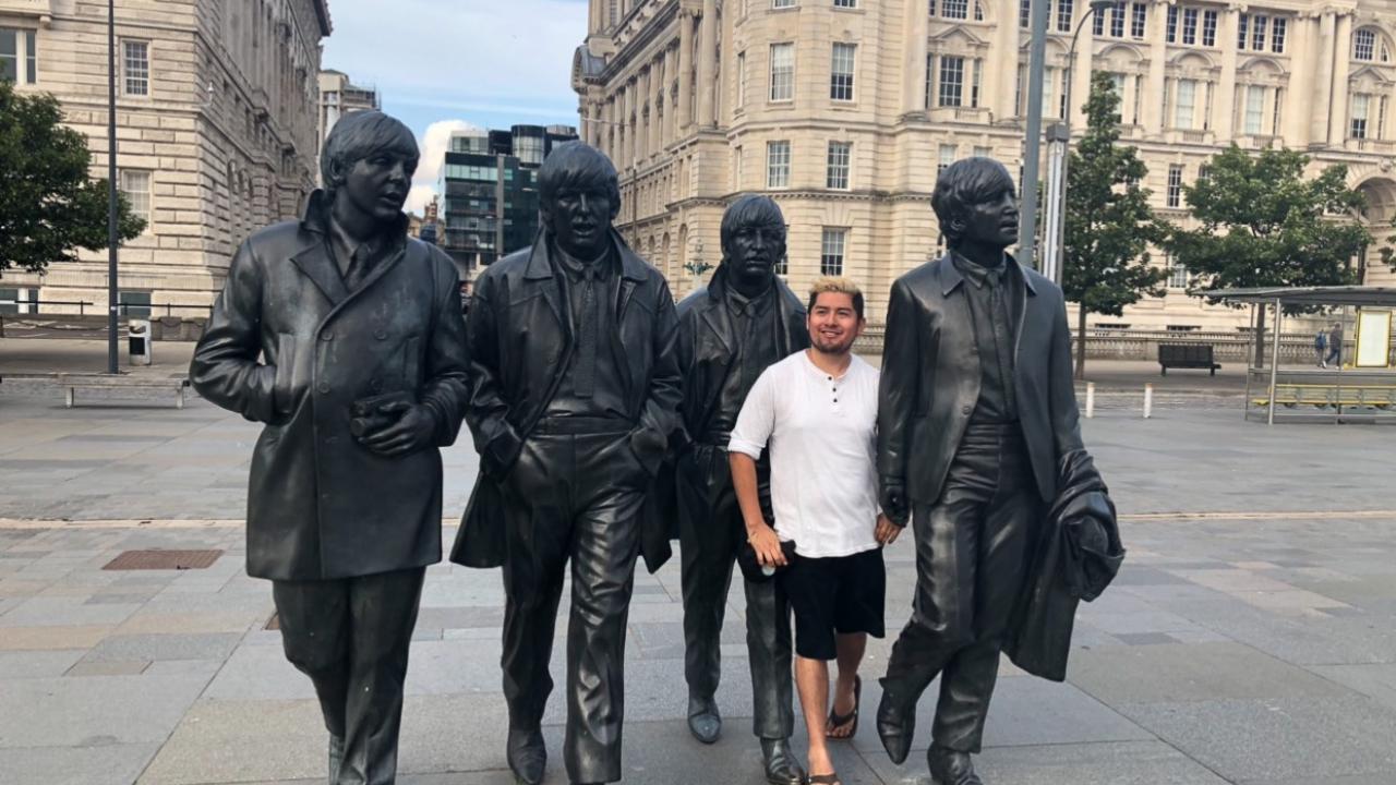 Gonzales stands among four metal statues of The Beatles on a London street.
