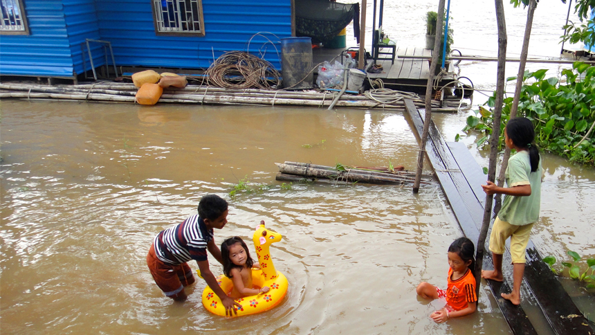 Children play in the water surrounding their floating homes.