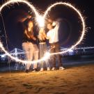 Students on a beach trying to use fireworks to make a heart shape.
