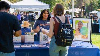 Photo of students gathered around a tabling getting information about global learning opportunities. They are outdoor at the Global Learning Fair on the UC Davis campus.