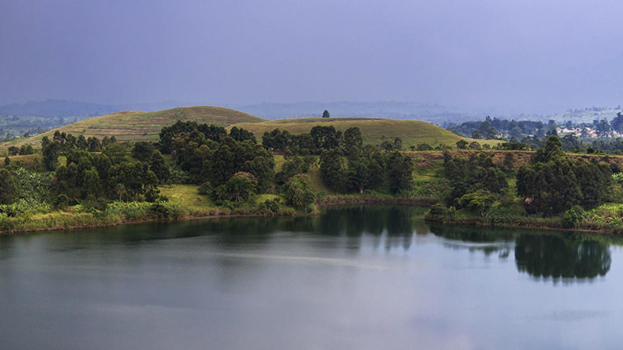 image of a lake in Uganda surrounded by greenery and mountains 