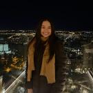 A student poses with a nighttime view of a city in the background
