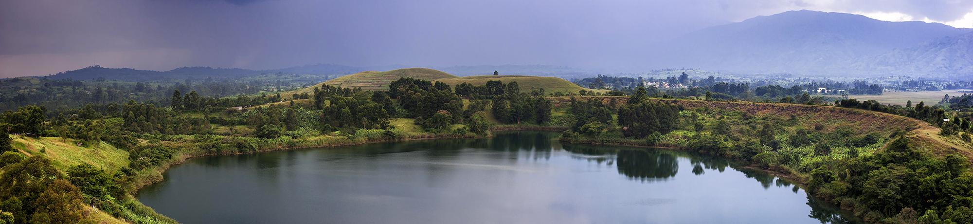 image of a lake in Uganda surrounded by greenery and mountains 