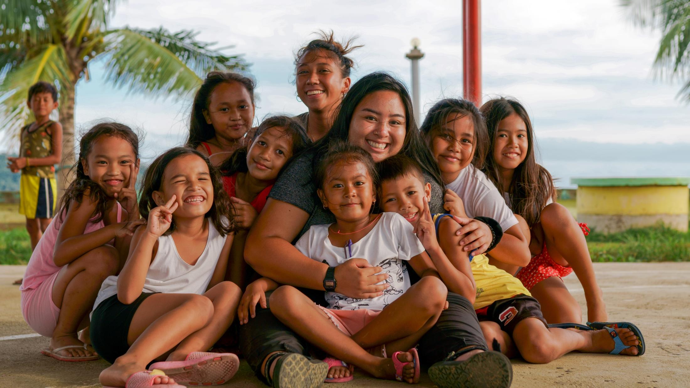 A group of kids pose for a picture, smiling and hugging