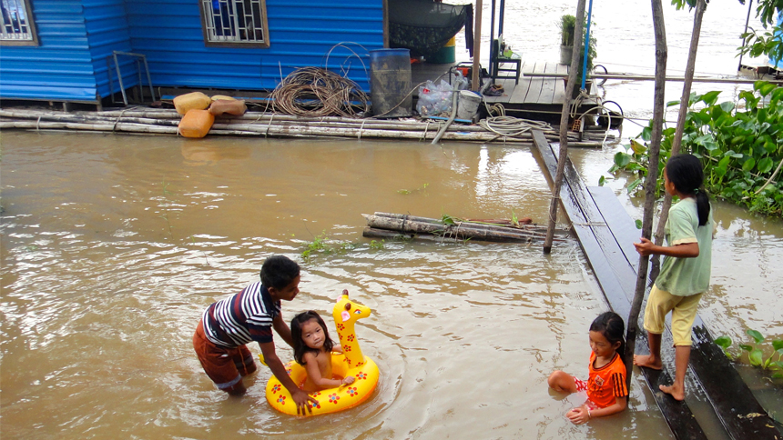 Children play in the water surrounding their floating homes.