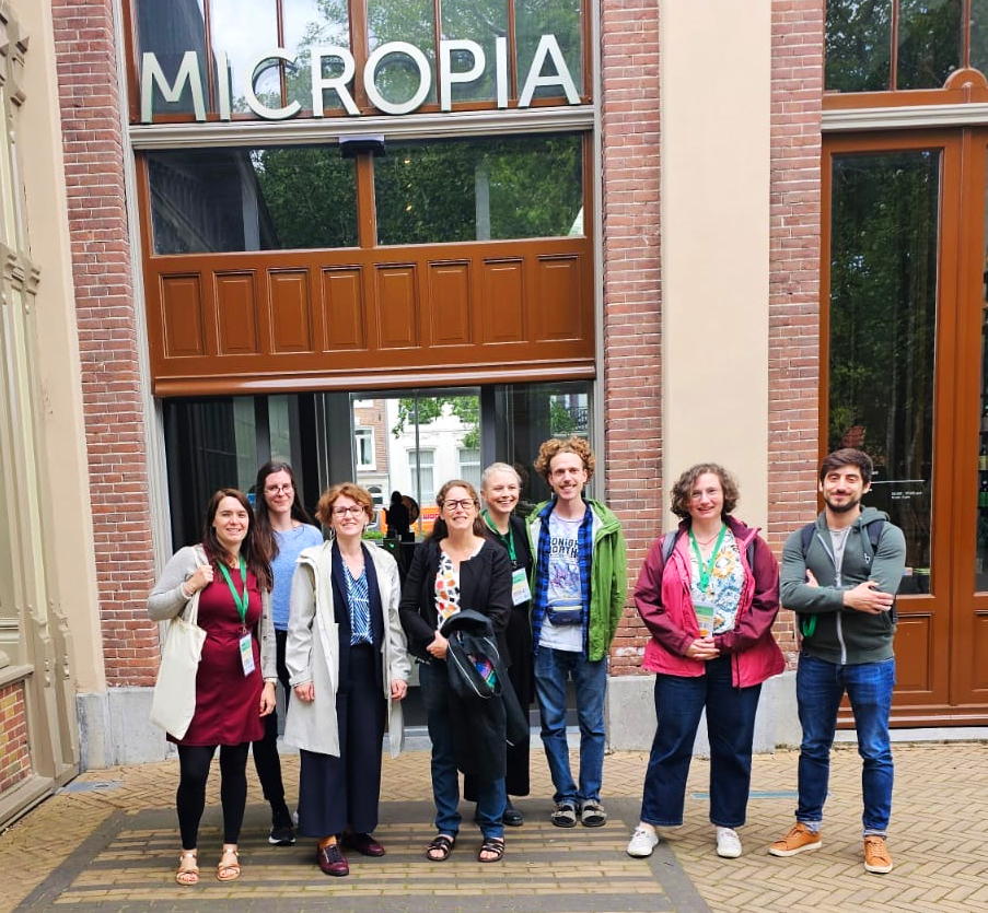 Group of people standing in front of Micropia entrance with brick and glass facade.