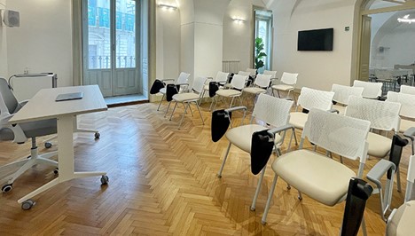 Modern classroom with white chairs and a large table on a wooden floor.