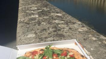 A photo of a big pizza with an iconic bridge in the background in Florence, Italy