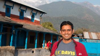 Student with a UC Davis Global Affairs t-shirt standing in front of a building