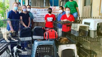 students standing behind multiple crates of dogs
