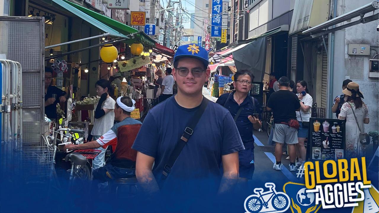 Aidan stands and smiles in a busy street.