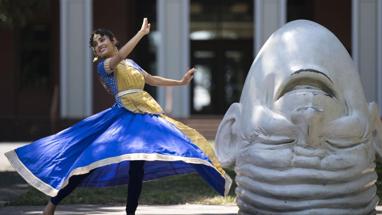 Vyoma dances in a blue skirt next to an Egghead.