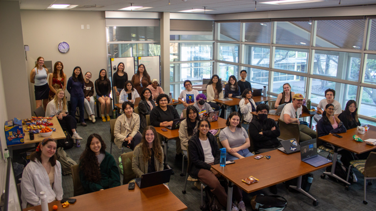 Students sit at their desks smiling for the camera