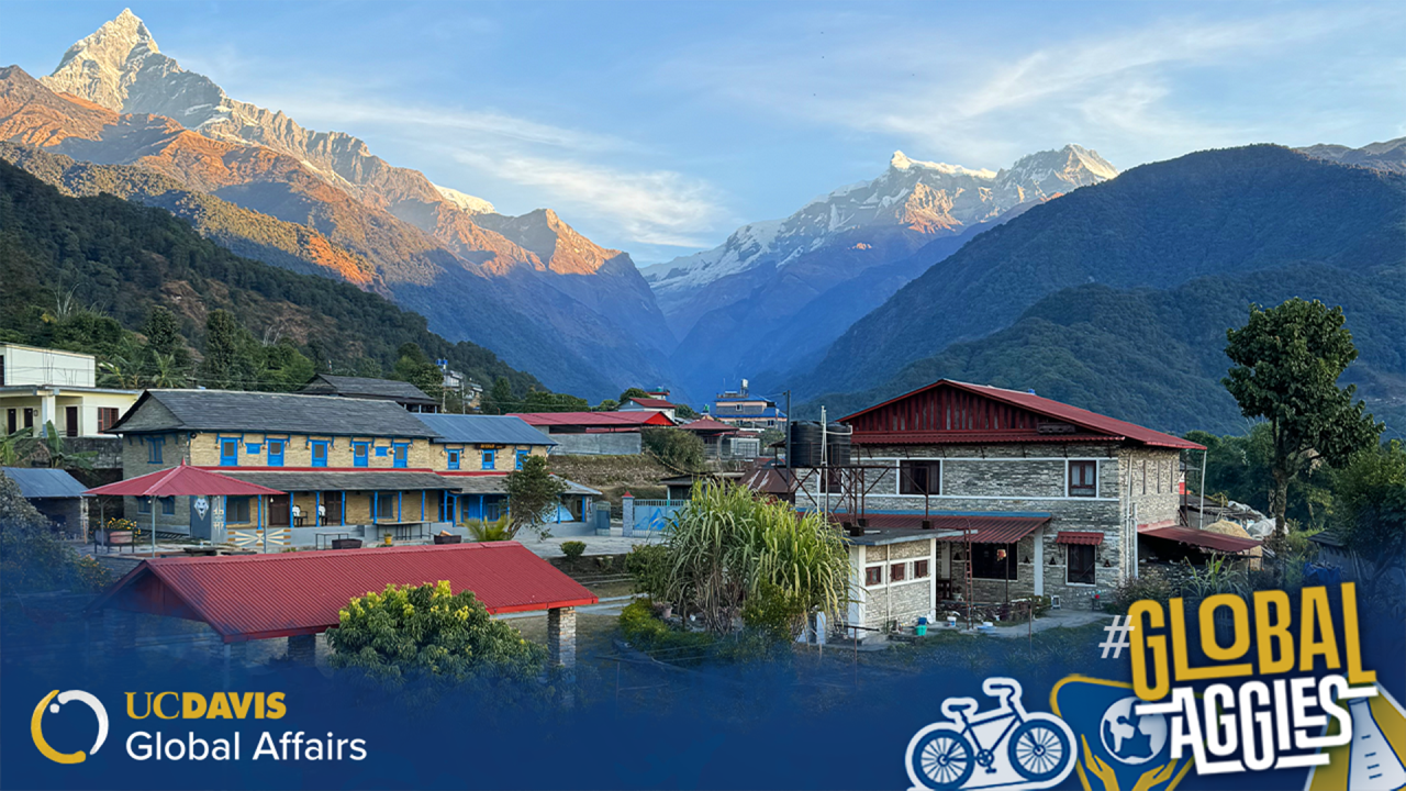 A scenic image of a snow-capped mountain peak at sunrise or sunset, with warm blue light casting over the summit and surrounding village. The UC Davis Global Affairs logo is in the bottom left corner, and the bottom right features the hashtag '#GlobalAggies' with illustrated icons of a bicycle, a globe, and a beaker.