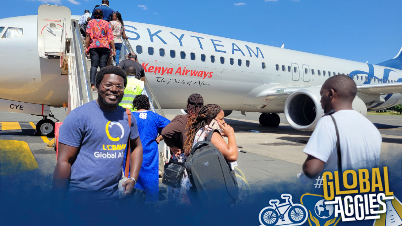 Roy Akumu smiles for the camera in front of an airplane.