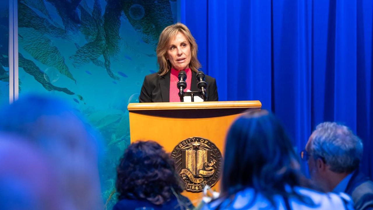 Cecelia Sullivan stands at a podium in front of a crowd of people.