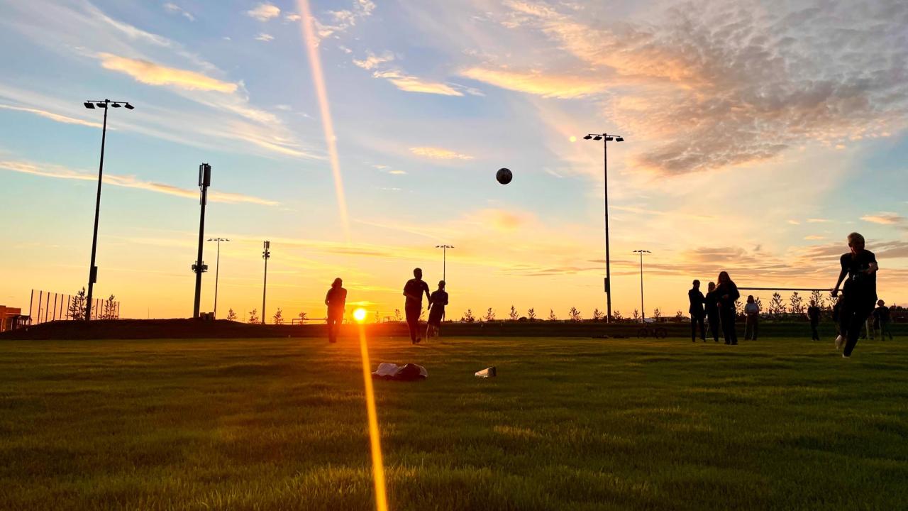 Photo of students playing soccer at sunset