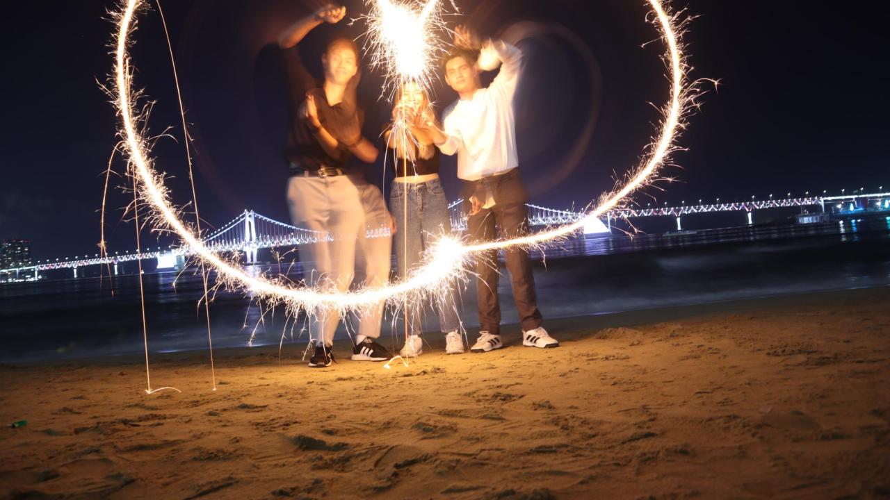Students on a beach trying to use fireworks to make a heart shape.