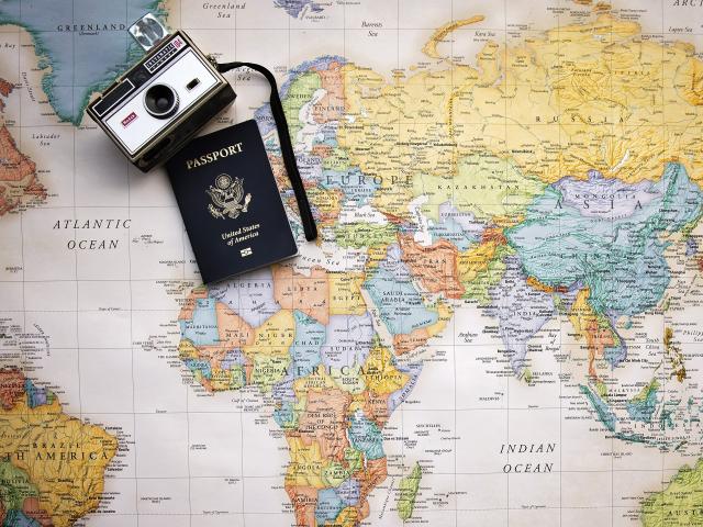 Photo of a map with a passport and camera in the upper left corning.