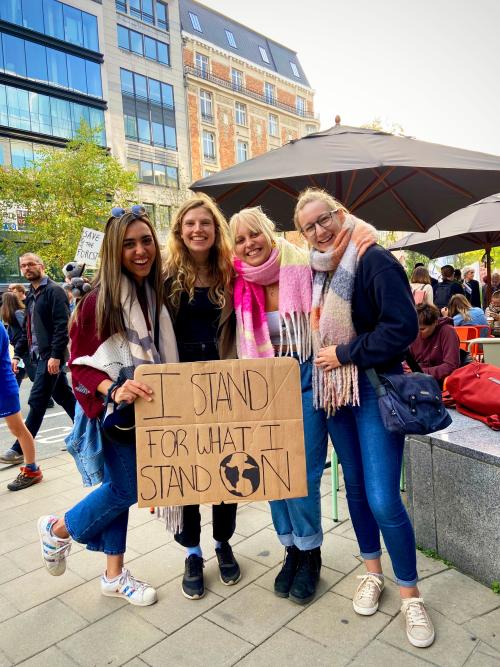Four students holding a sign that reads "I stand for what I stand on" with the large globe in place of the 'o' within the word 'on'
