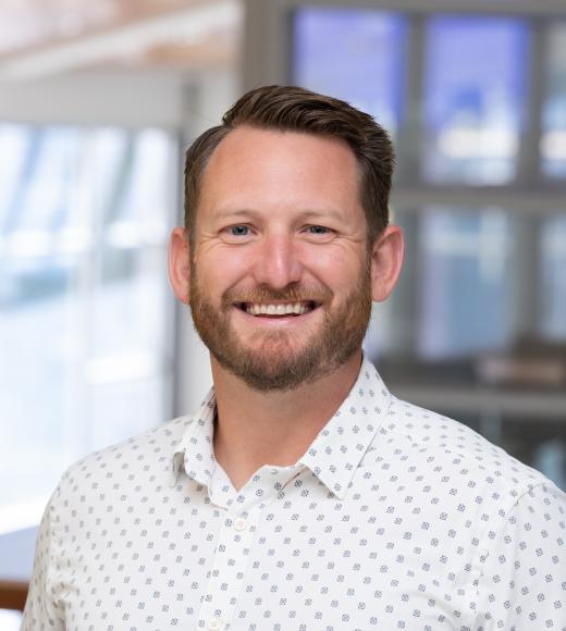 Chris Reeder smiles wearing a white button up in the International Center.