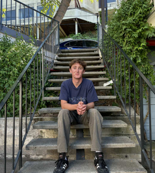 Connor Drew sitting on stairs and smiling.