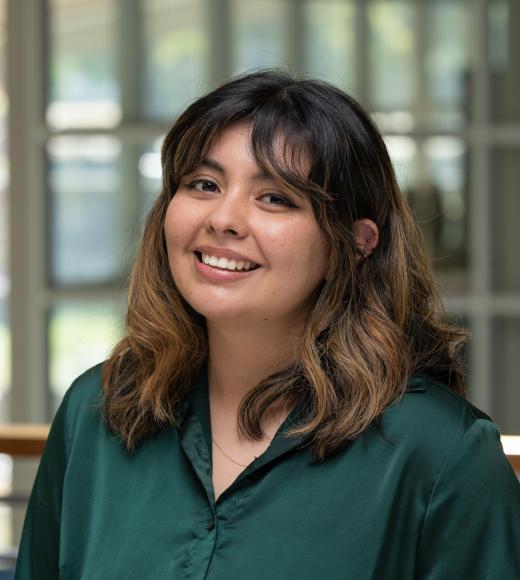 Mariana smiles in a green button up inside the International Center.