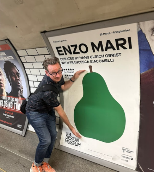 Professor Tim McNeil poses in front of a pear graphic art wall.