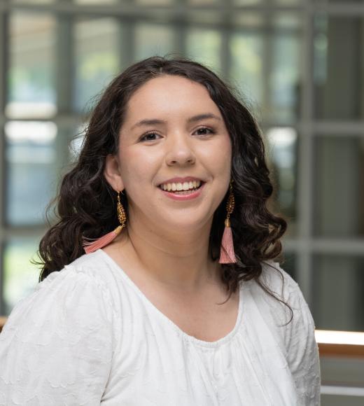 Stephanie smiles in a white blouse inside the International Center.