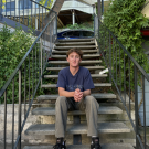 Connor Drew sitting on stairs and smiling.