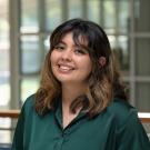 Mariana smiles in a green button up inside the International Center.