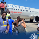 Roy Akumu smiles for the camera in front of an airplane.