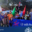 Student standing together in front of a large banner that reads "Up with People". They are holding flags of different countries.