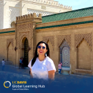 Student standing in front of a large stone building in the city of Rabat.