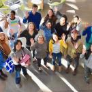 A group of students and staff looking up towards the camera, smiling and waving