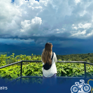Student looking out over a see a of green trees. It is a very cloudy day. A graphic is at the bottom with text: Global Aggies.
