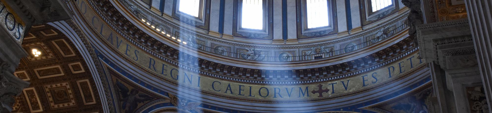 Photo on the inside of a large European building, with sun rays shining through the windows