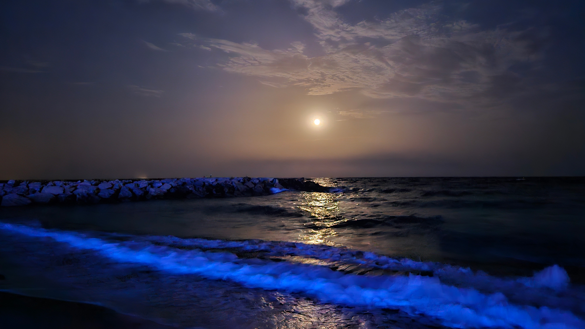 Sun setting as blue waves splash on the beach