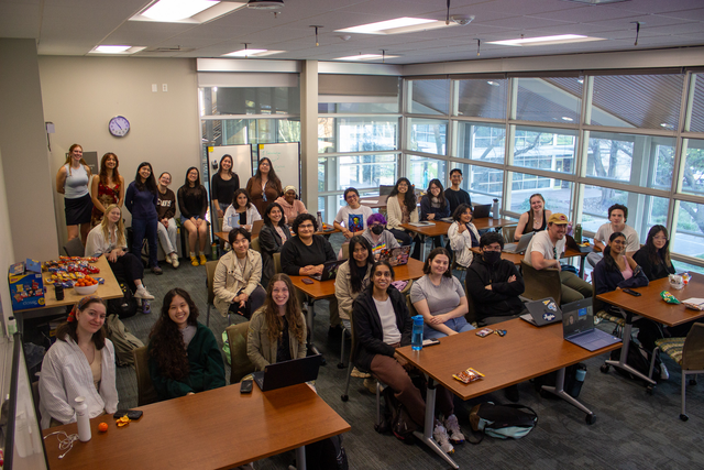 Students sit at their desks smiling for the camera